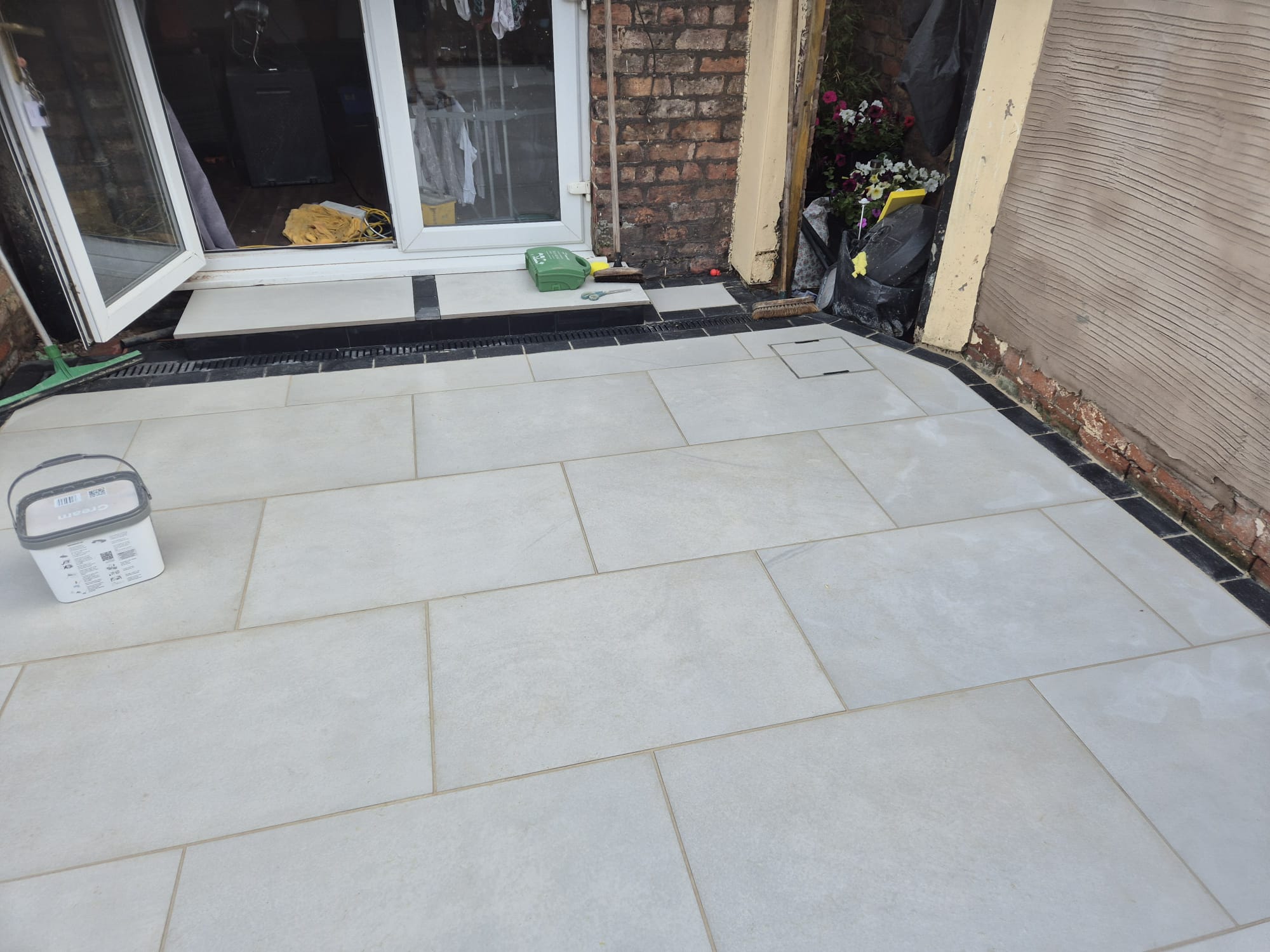 Grey porcelain patio with black brick border by patio doors