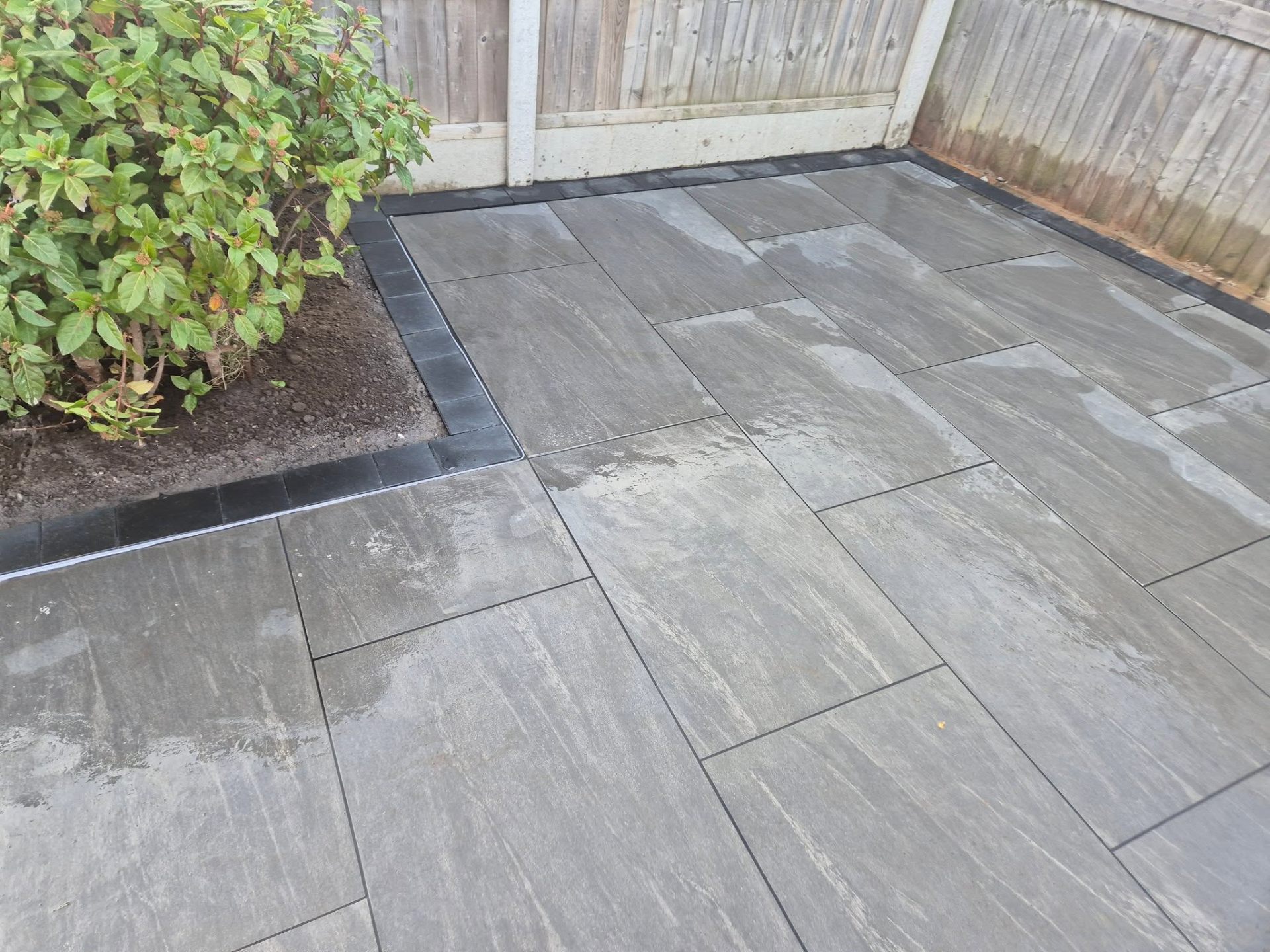 Grey porcelain patio with black brick border
