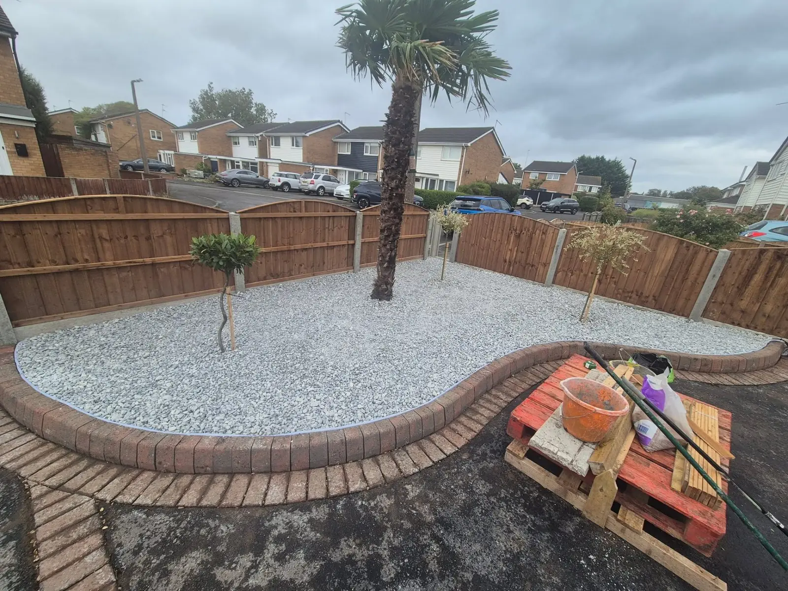 Curved gravel bed with brick border and mature palm