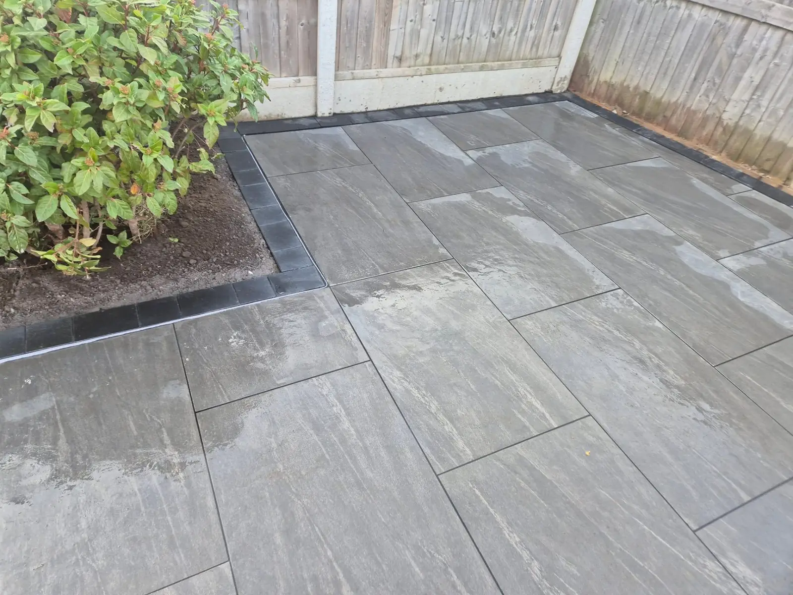 Porcelain patio finished with a crisp black brick border