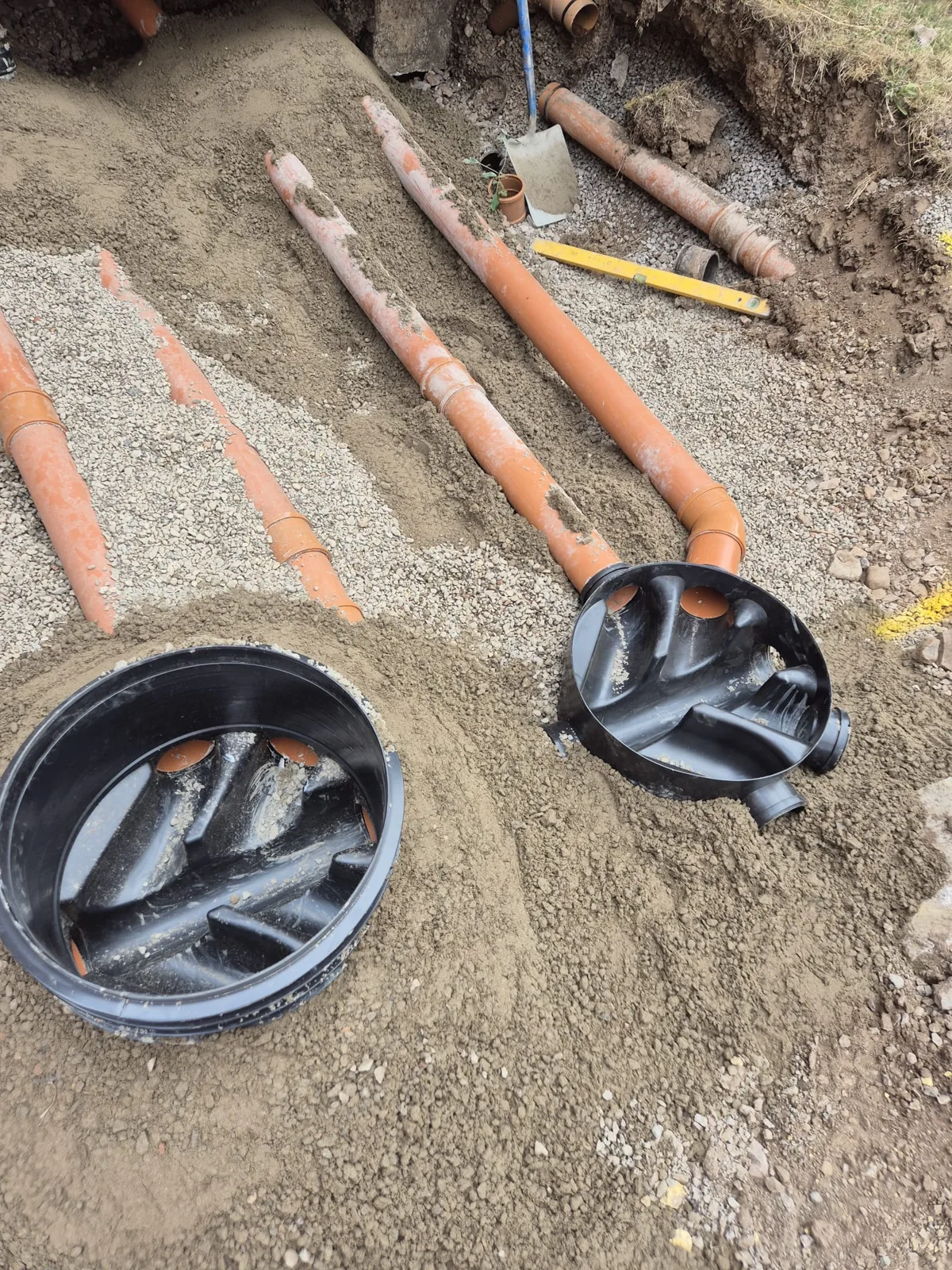 Two plastic inspection chambers set into a gravel bed with new underground drainage pipes