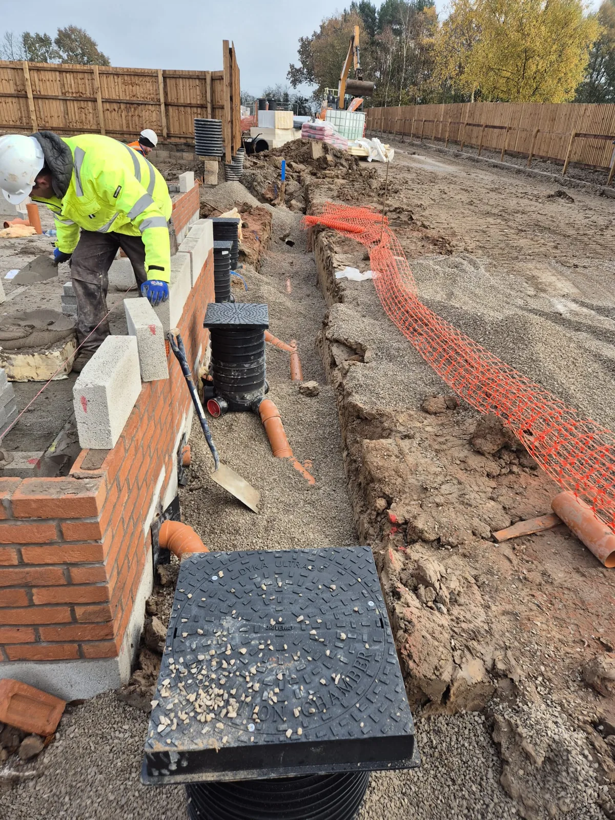 A brick retaining wall built alongside a drainage chamber and service trench