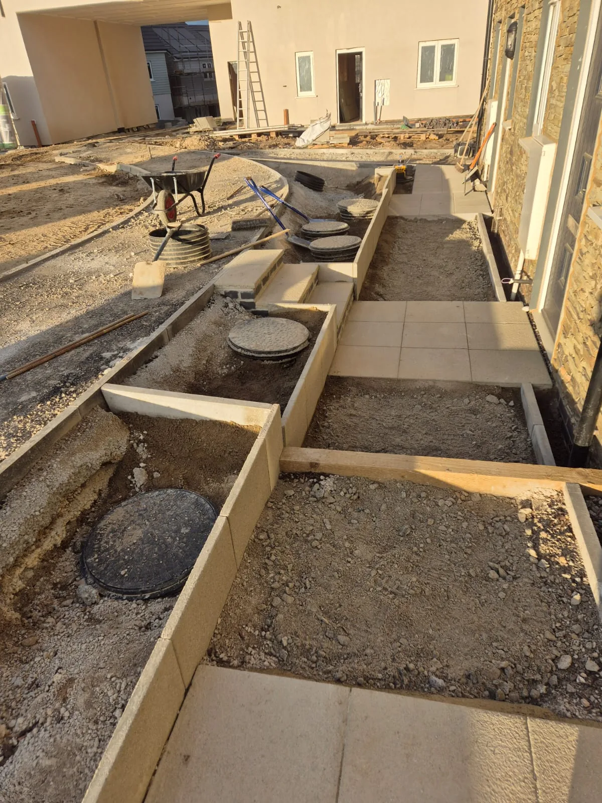 A terraced garden with retaining walls, paved paths and inspection chambers set to level