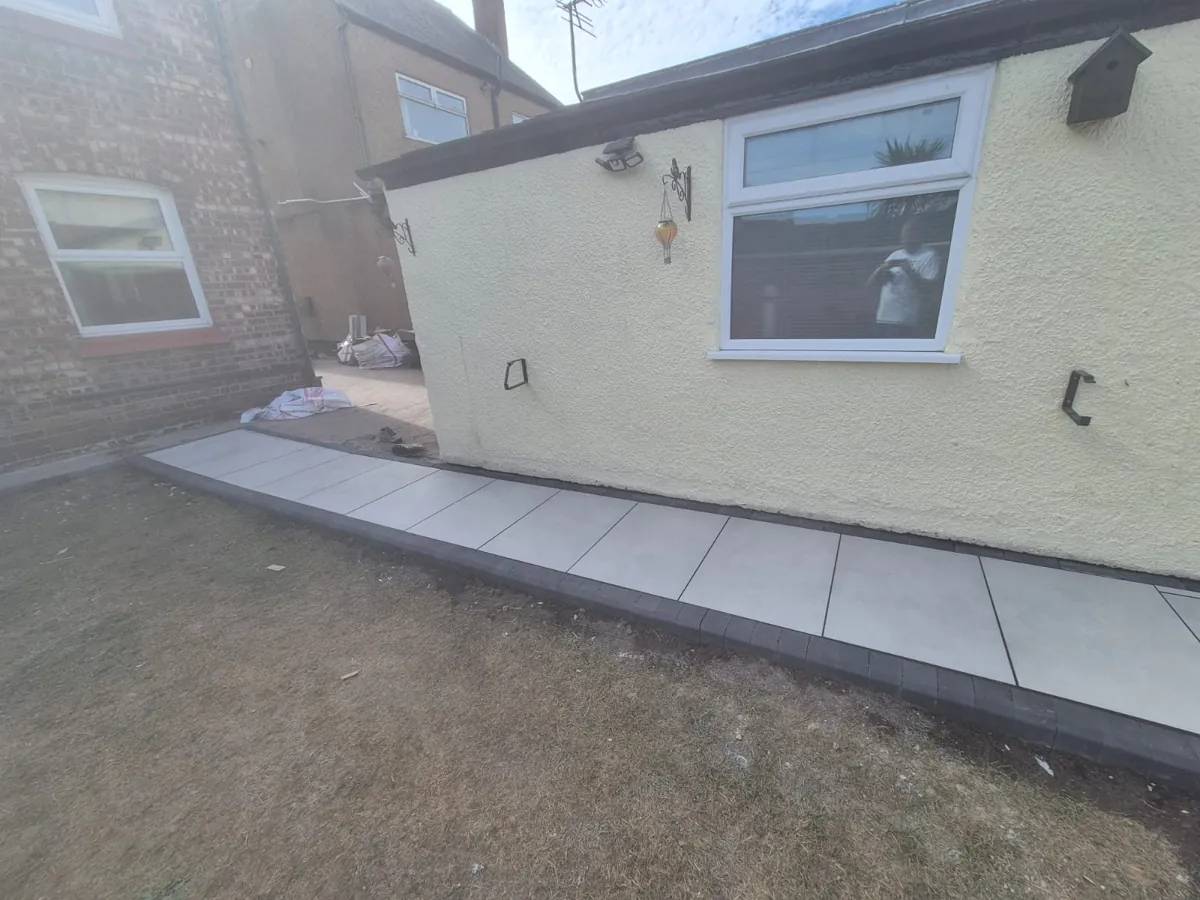 Wrap-around white porcelain side path in Wallasey running to the garage with a dark coping edge