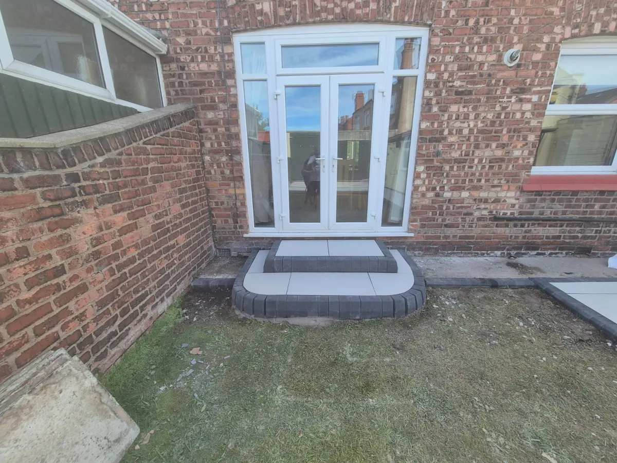 New porcelain step up to French doors in Wallasey with a curved dark block-paved edge