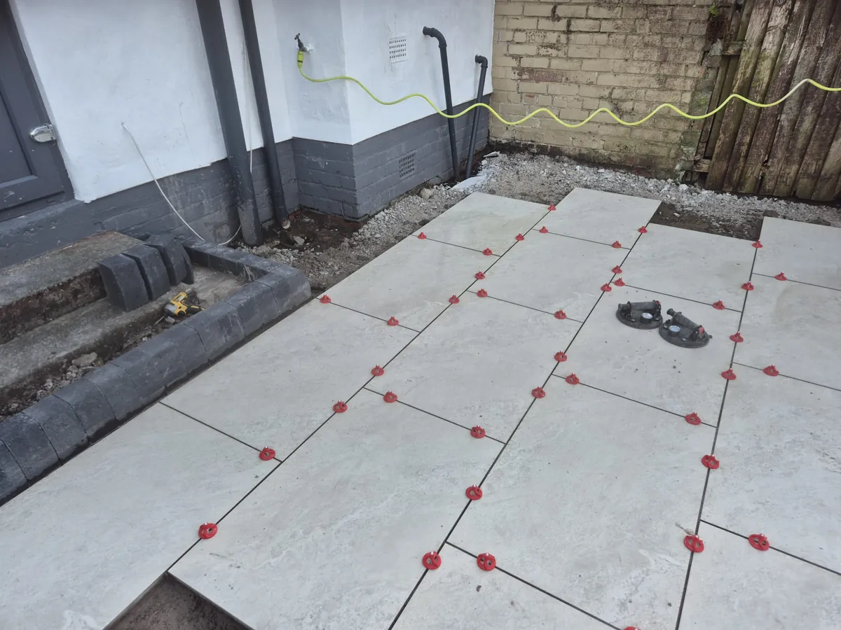 A light porcelain patio against a charcoal block border and step in Birkenhead, most of the paving now laid