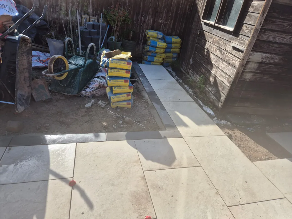 Porcelain paving brought around the shed and along the rear boundary in Birkenhead, with charcoal block edging framing the run
