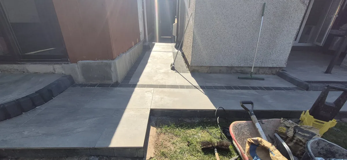 Wide view of a charcoal porcelain patio with a contrasting dark setts border