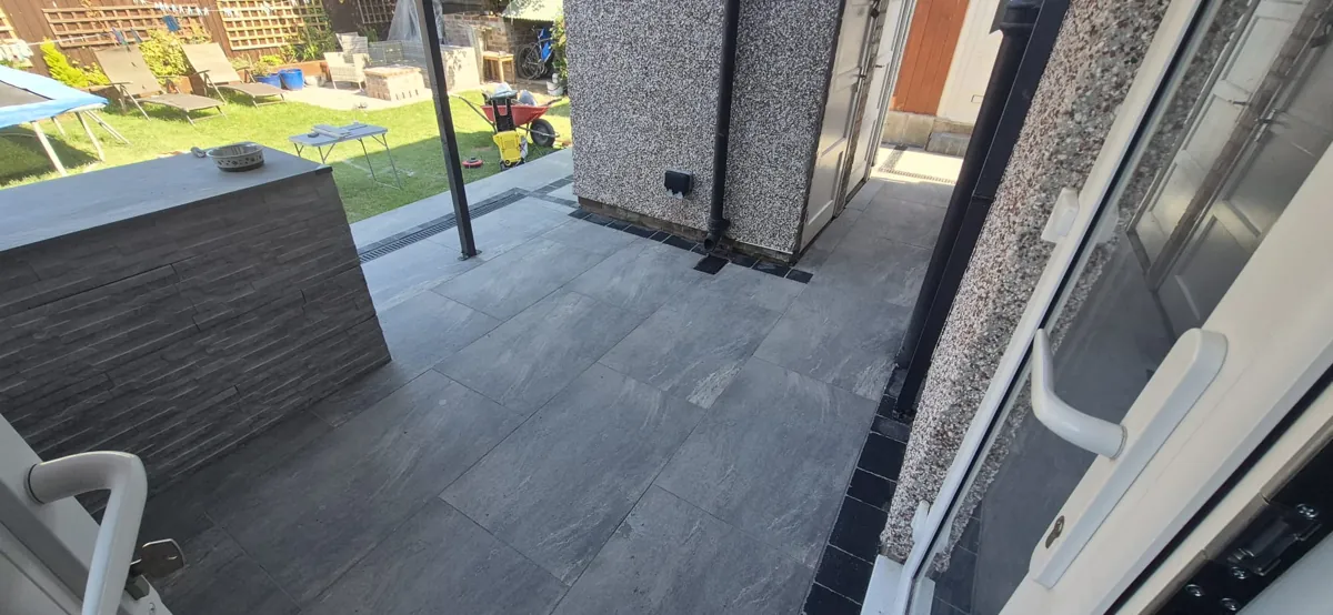 Charcoal porcelain patio with a stacked-stone clad outdoor bar and a garden room behind