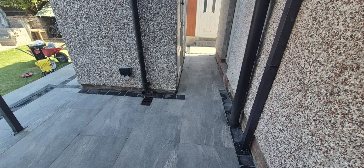Charcoal porcelain path running down the side passage to a white door with a dark setts border
